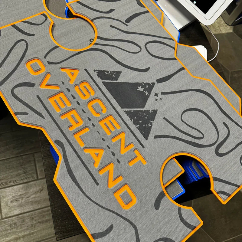 Load image into Gallery viewer, Close-up of gray Ascent Overland branded vehicle floor mat with orange trim and black topographic map design
