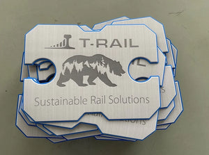 Stack of T-RAIL sustainable rail solutions branded metal tags with bear and forest design