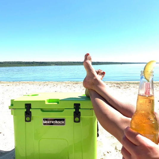 Relaxing at sandy beach with lime green WhiteRock cooler and person holding beer bottle with lime wedge