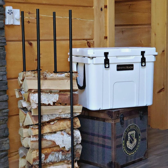 White WhiteRock cooler on rustic wooden trunk next to stacked firewood in log cabin interior