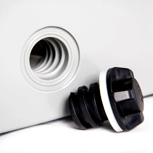 Black rubber stopper with white gasket beside threaded white plastic opening